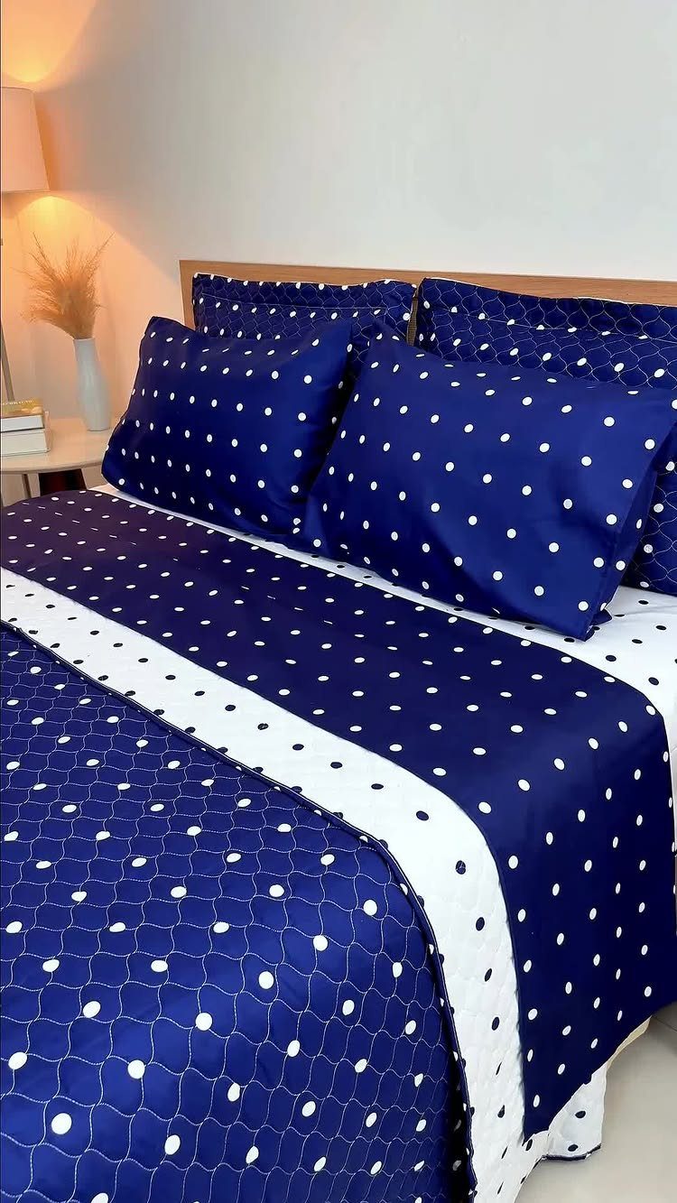 Dark blue polka dot bedding on a bed in a simple white room.