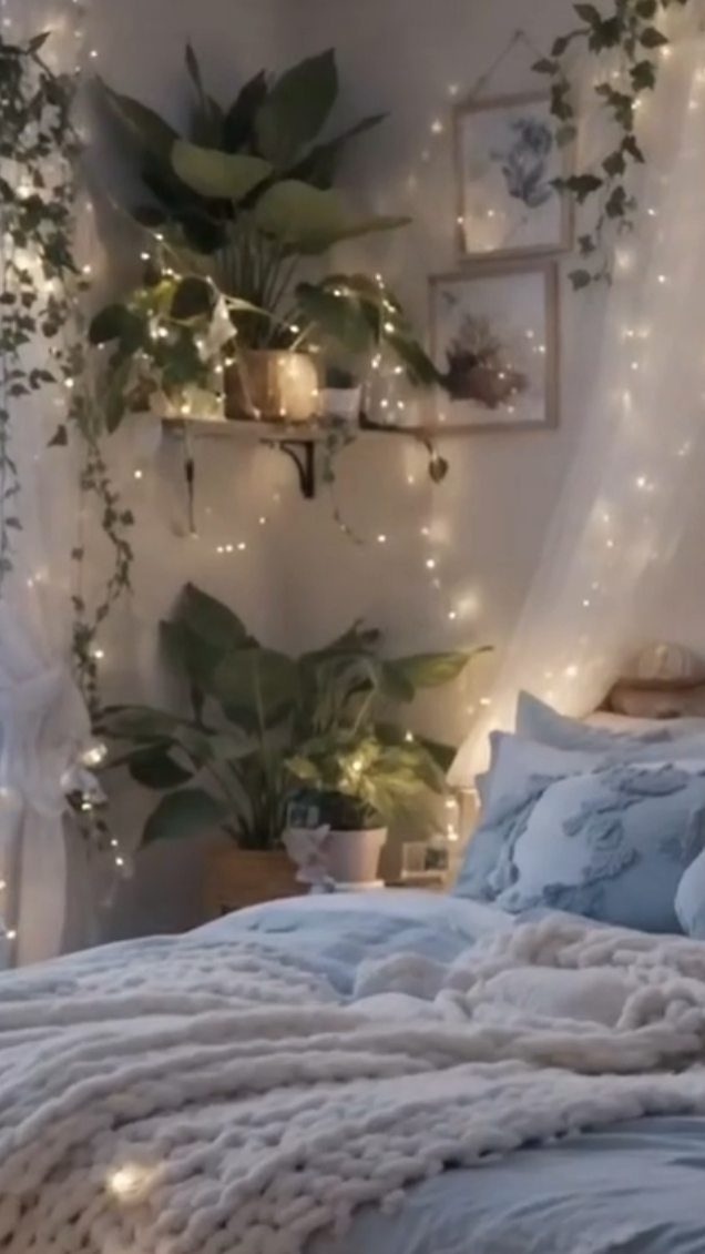 Powder blue bedding and white knit throw with fairy lights and indoor plants.