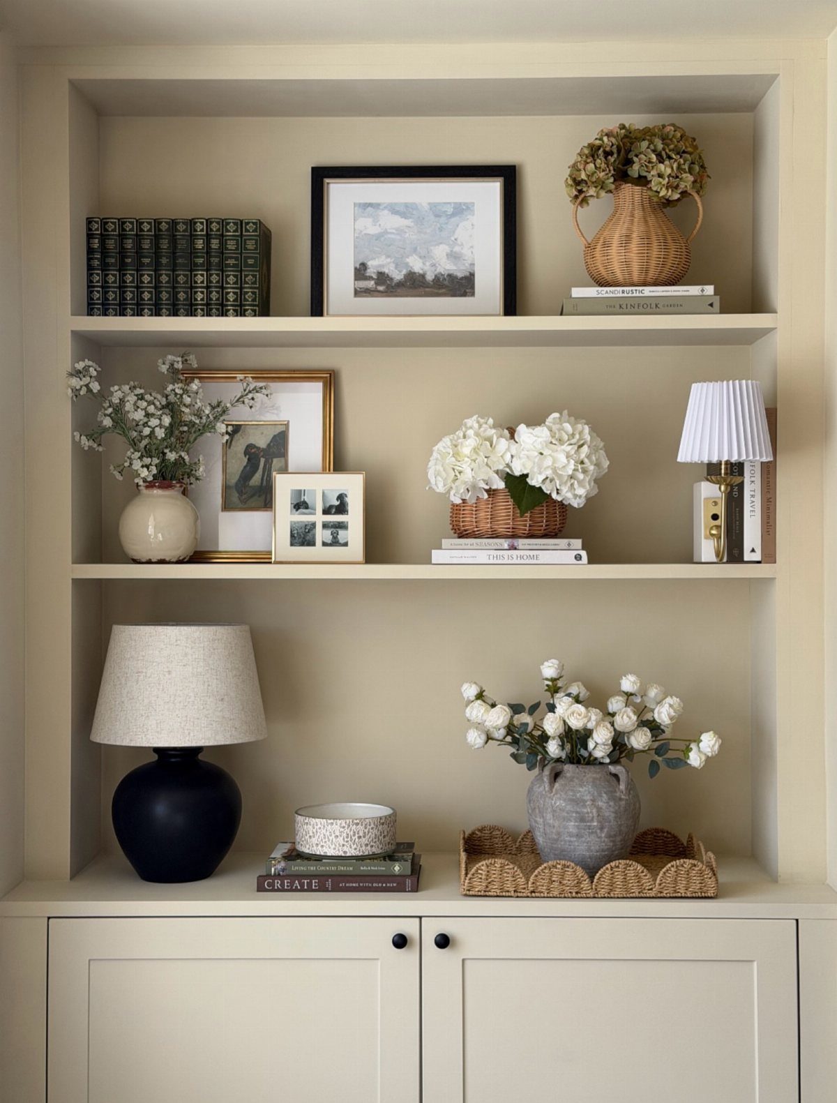 Built-in alcove shelves with books, floral arrangements, and decorative lamps in beige tones.