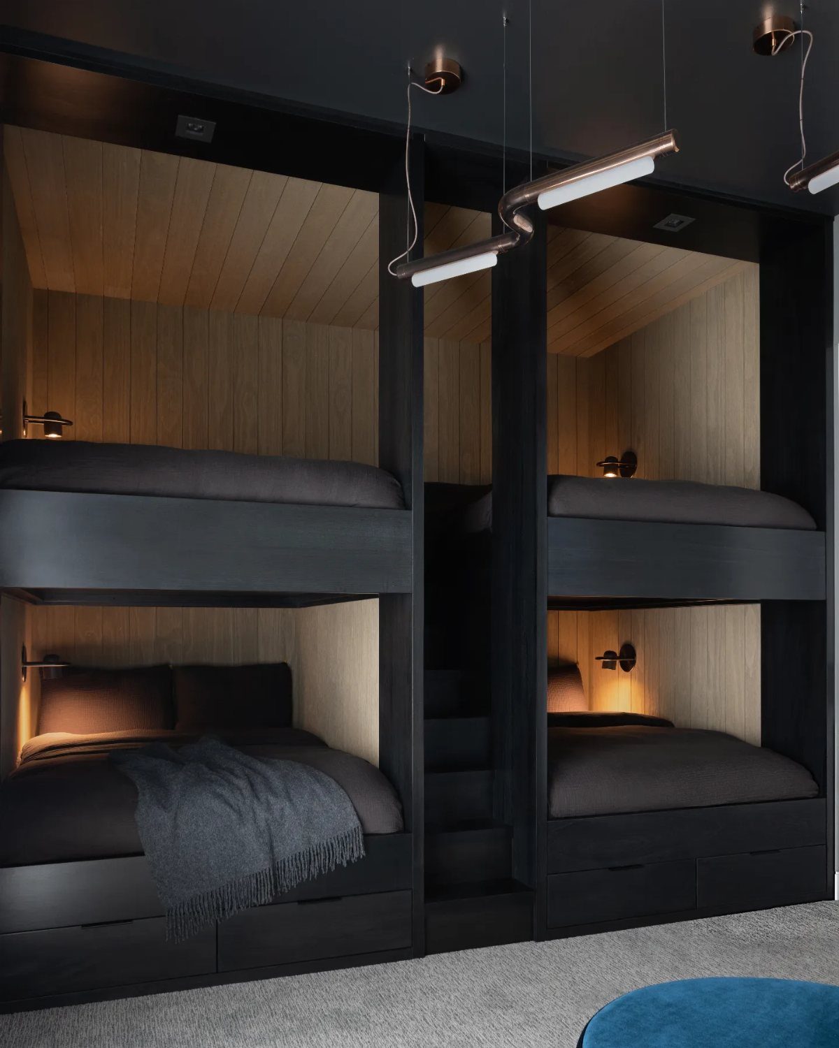 Black built-in bunk beds with light wood interiors and integrated reading lights.