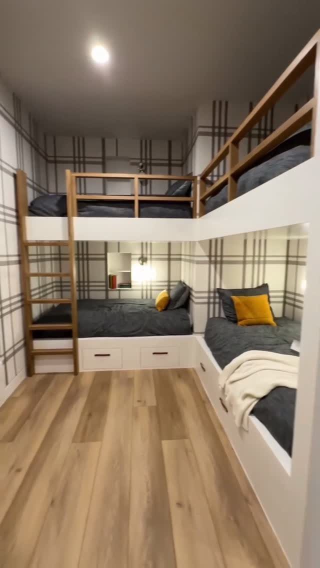 White wall-to-wall built-in bunk beds with wooden accents and grey bedding in a bedroom.