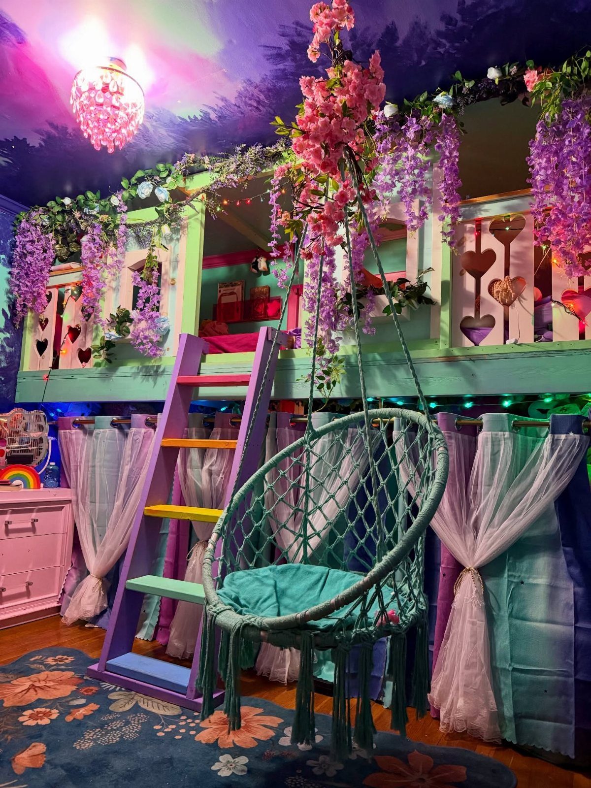 Colorful built-in bunk bed with floral decorations, purple ladder, and teal hanging chair.