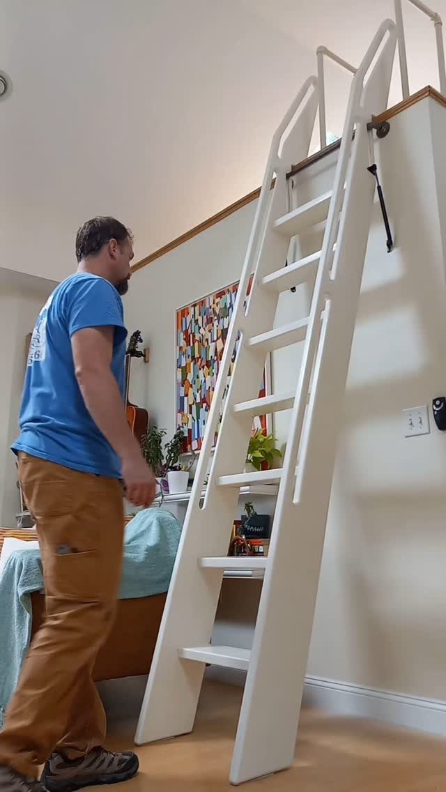 White wooden ladder leading to a built-in loft bed with a man standing nearby.