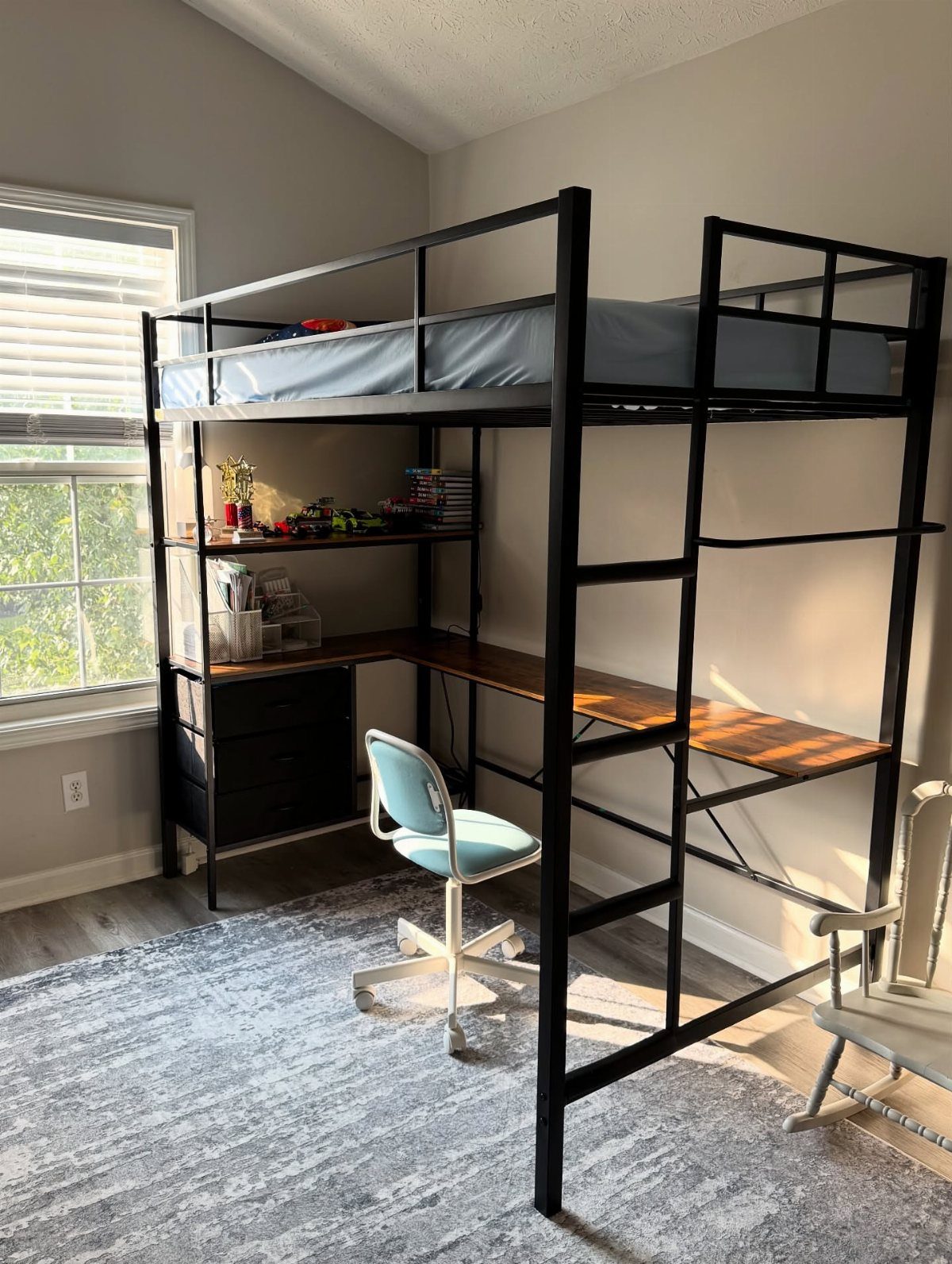 Black metal loft bed with a built-in desk and drawers underneath.