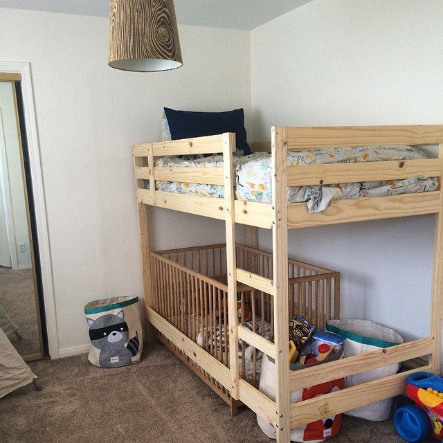 Wooden bunk bed with a built-in crib on the bottom level in a bedroom