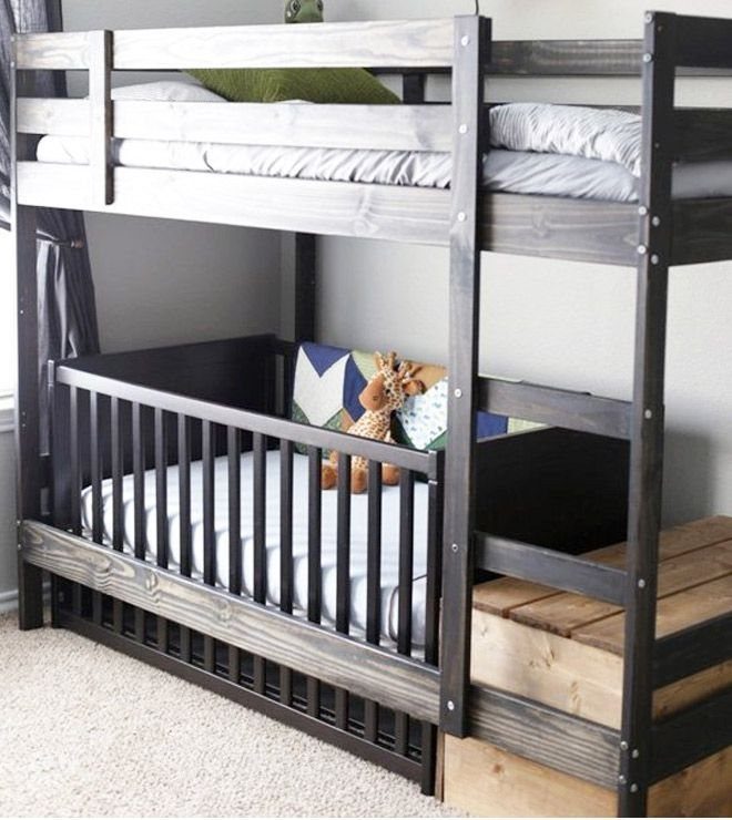 Grey wooden bunk bed with a matching crib integrated underneath in a bedroom.