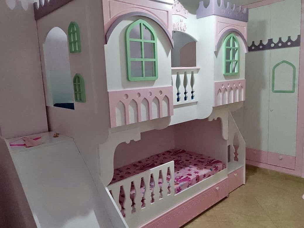Pink and white castle bunk bed with a slide and decorative green windows.