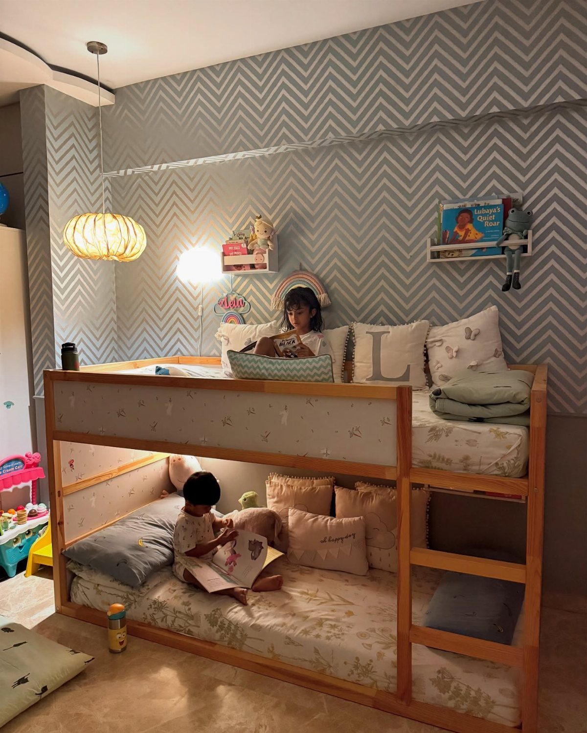 Child reading a book in a cozy bunk bed nook with soft pillows.