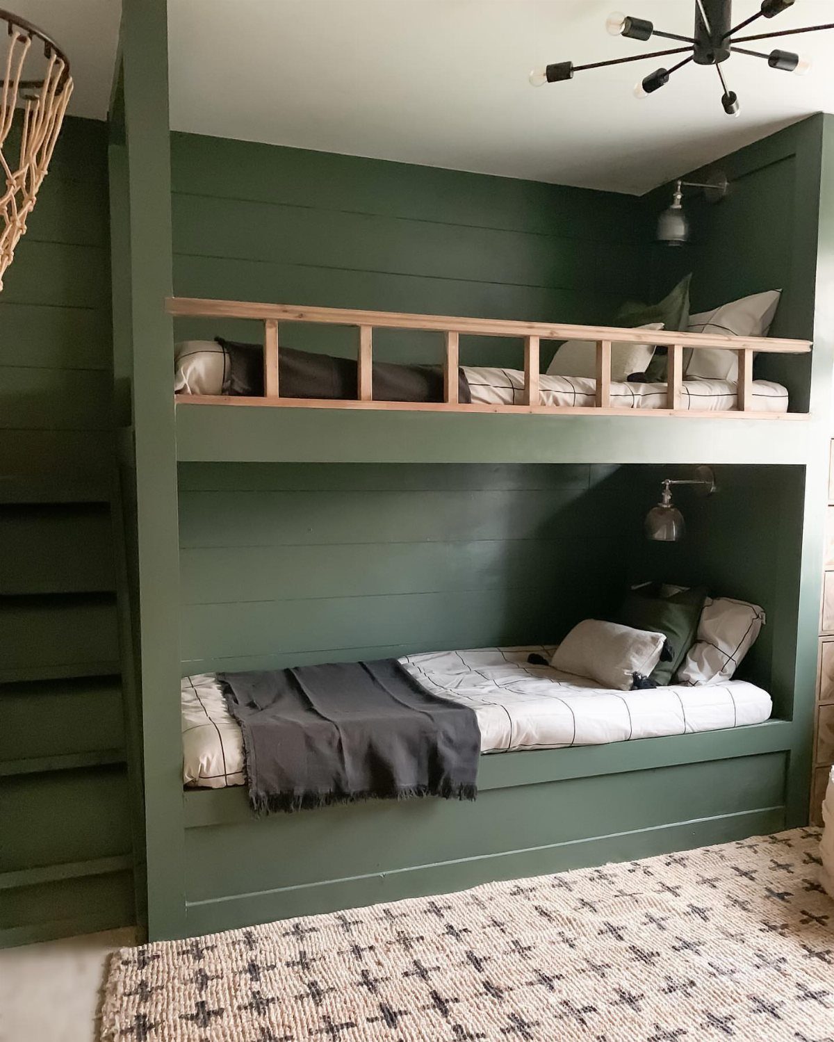 Green built-in bunk beds recessed into a wall with a patterned area rug.