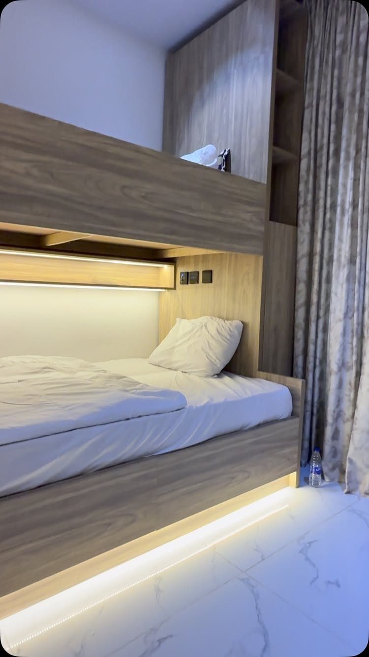 Wooden bunk beds built into a closet nook with white linens and warm lighting.