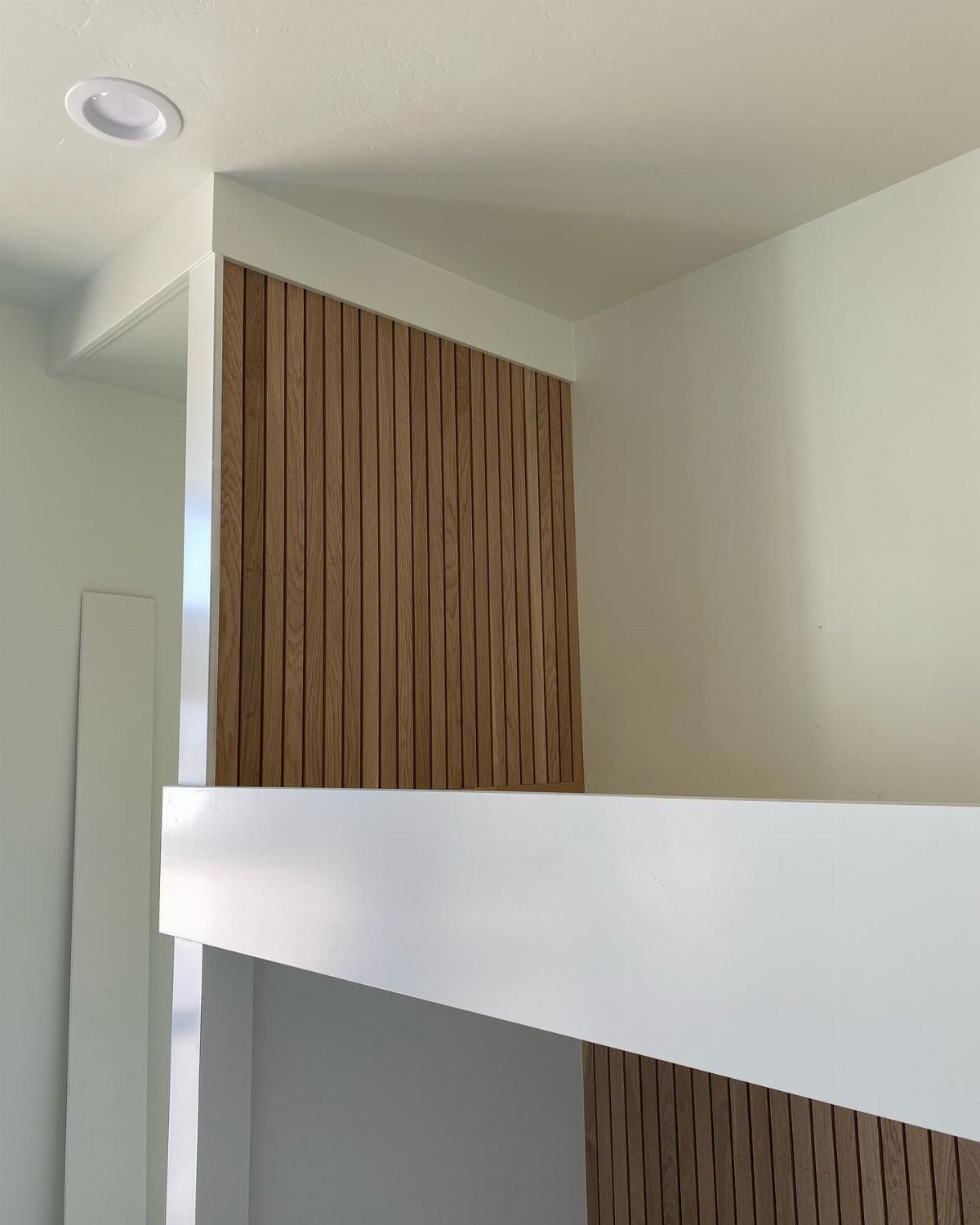 White bunk bed built into a closet with a wood slat accent wall.
