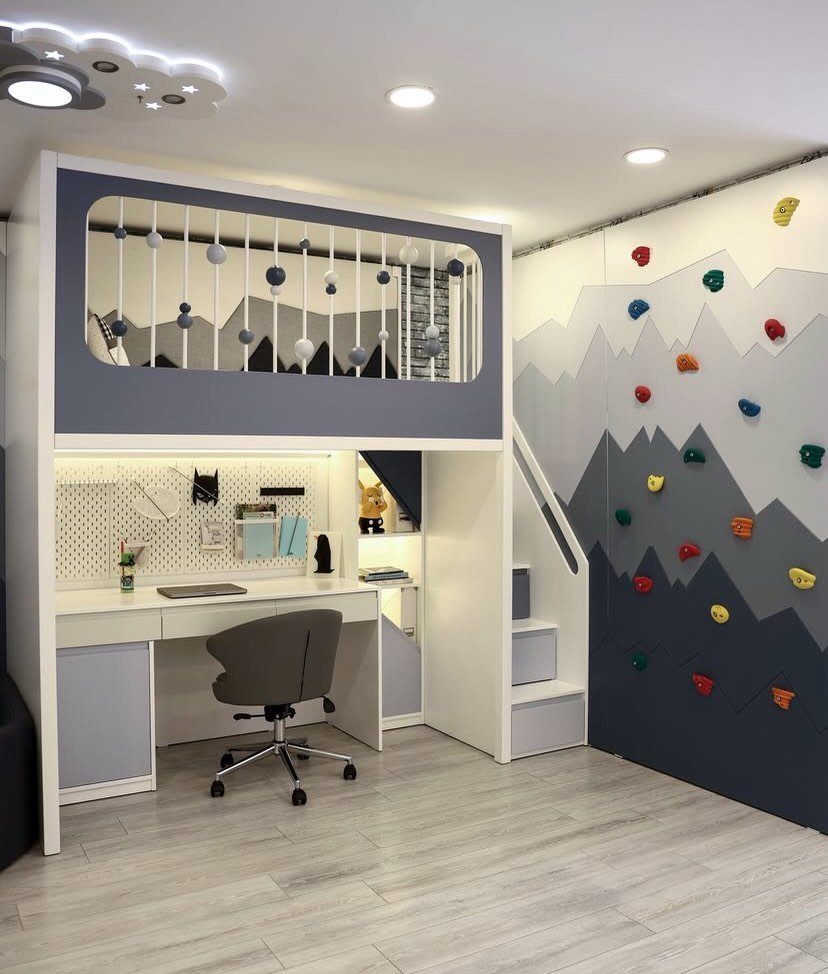 Loft bed with integrated desk and a colorful climbing wall in a bedroom.