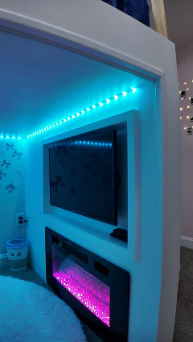 Blue LED strip lights illuminating the ceiling of a white loft bed area