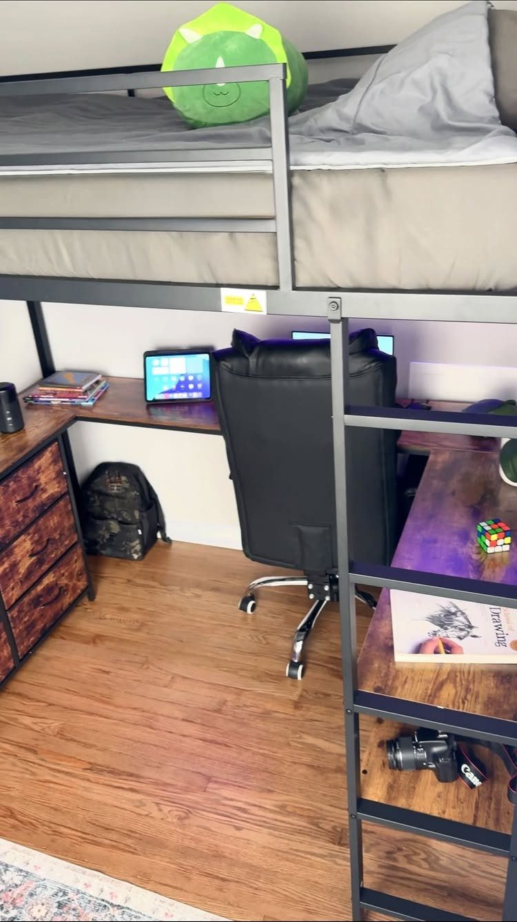 Black metal loft bed with a wooden desk and office chair underneath.