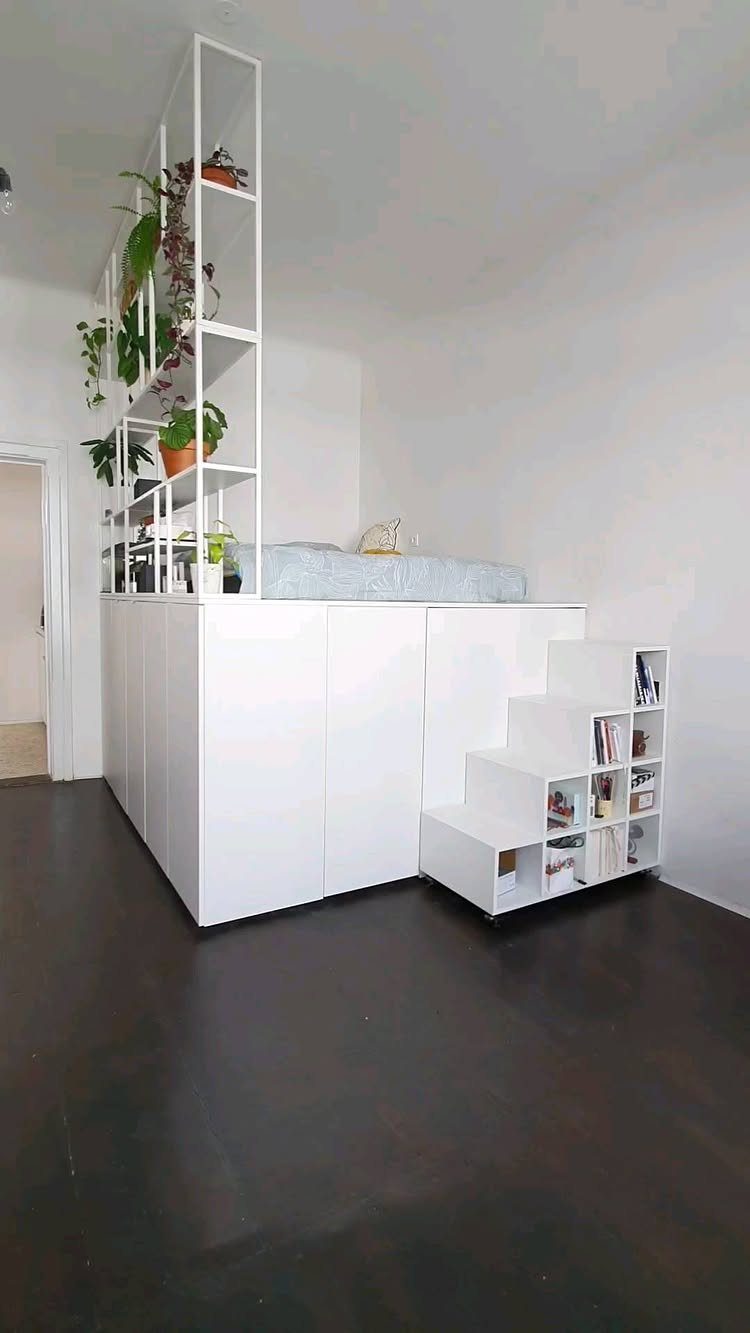 White loft bed with integrated storage cabinets and stairs containing bookshelves