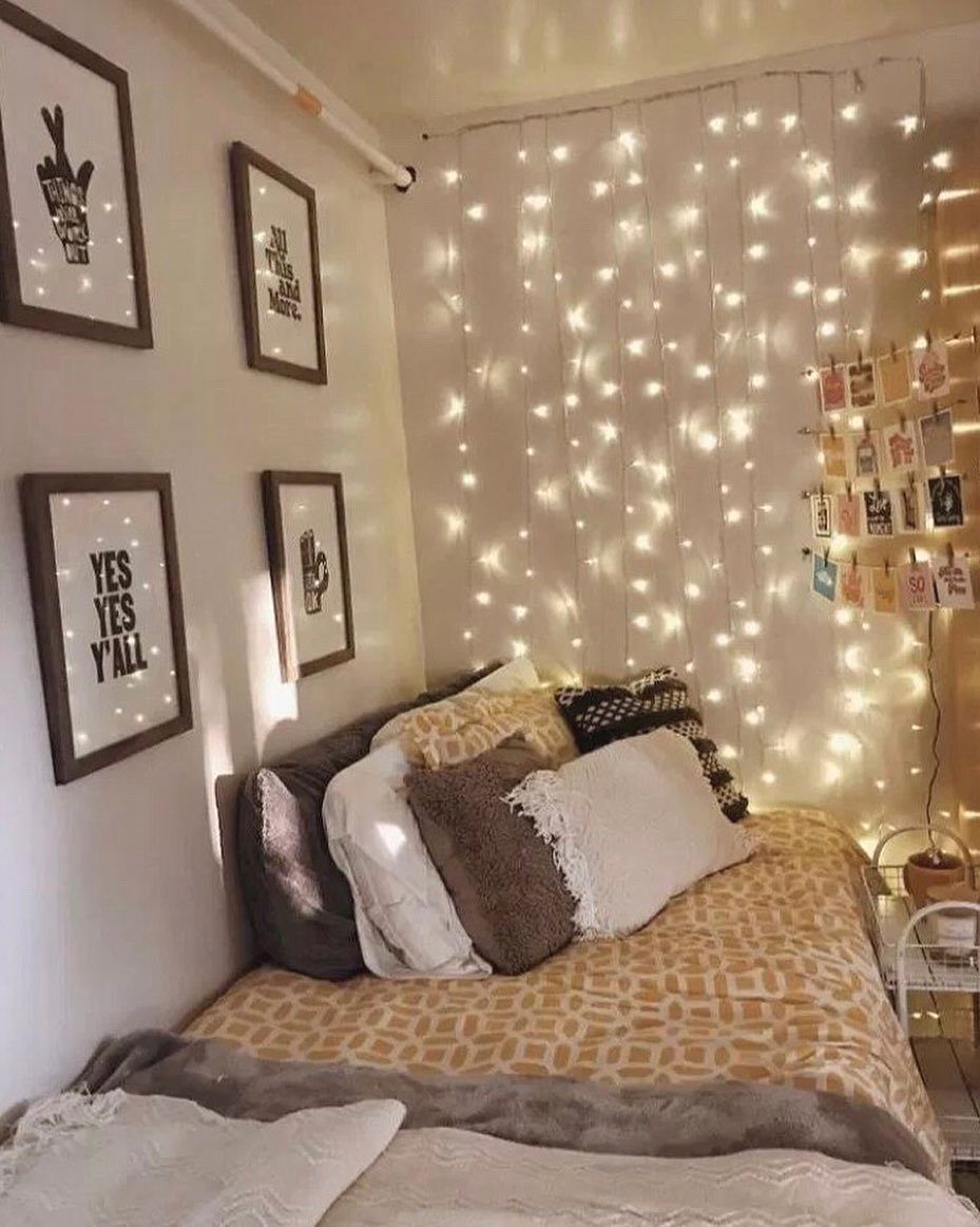 Bed with yellow sheets and pillows in front of a wall of fairy lights