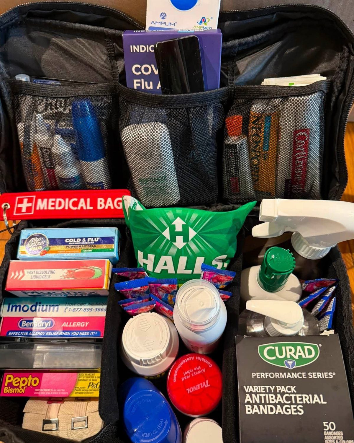 Open black medical bag containing bandages, medications, and cough drops for first aid.