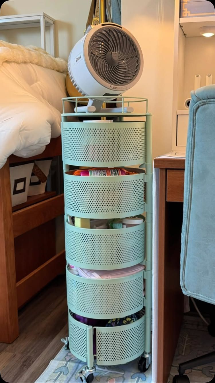 Mint green rolling storage cart with a white fan on top in a bedroom