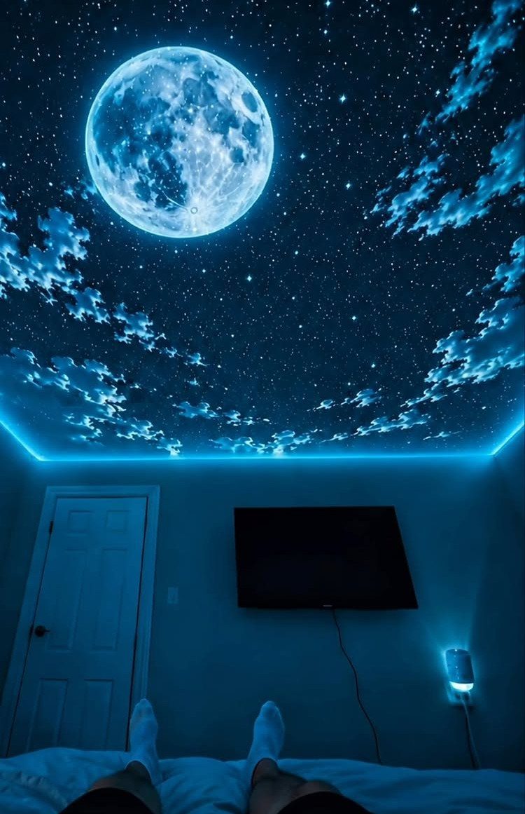 Starry night sky and moon projected on a bedroom ceiling with blue lighting.