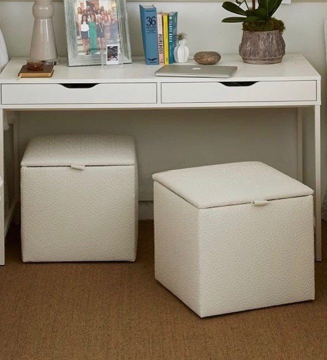White desk with storage ottomans, laptop, and decor in a small room
