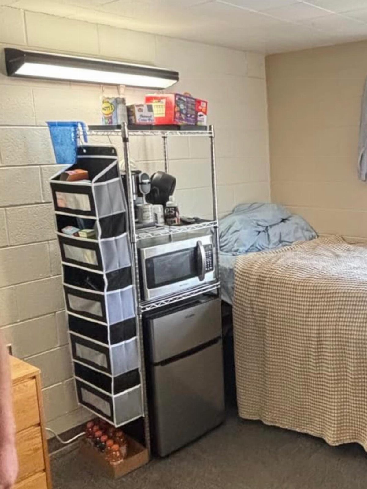 Small black mini fridge and microwave on a metal shelf in a dorm room.