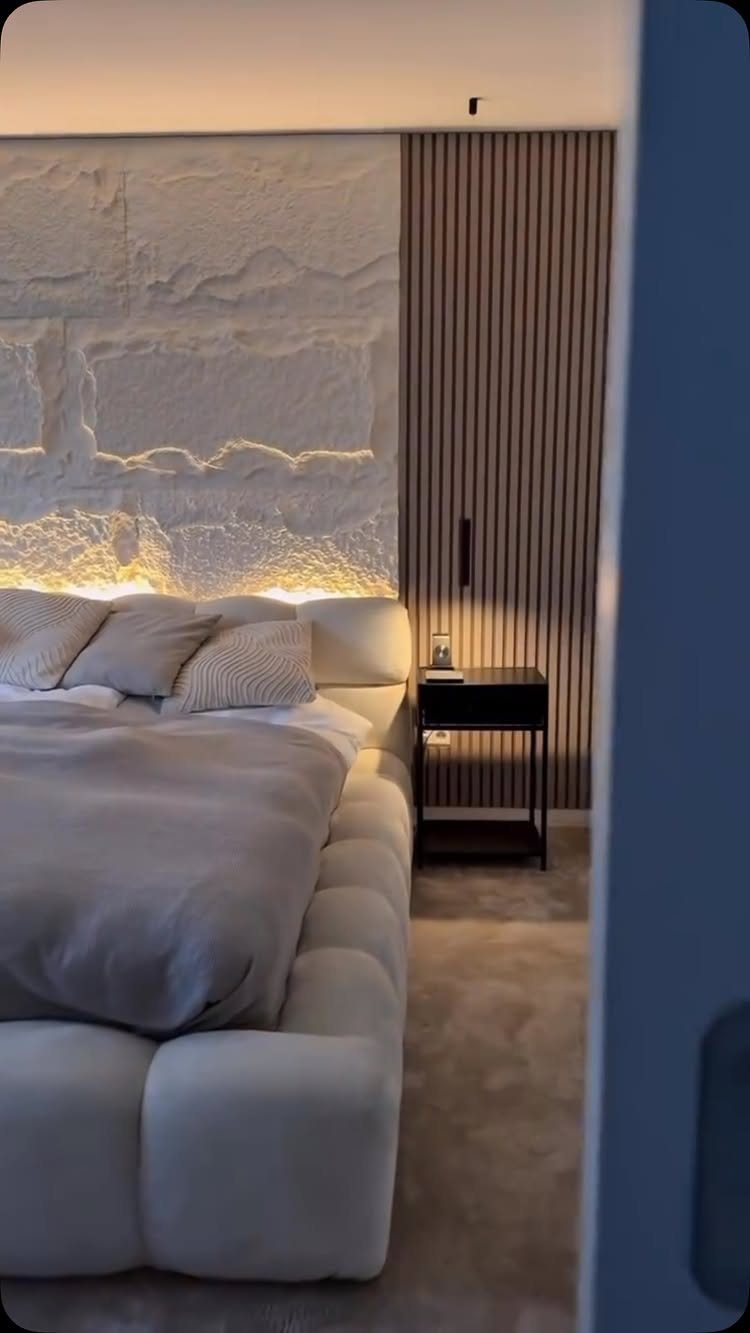 White textured stone feature wall with warm lighting in a modern bedroom
