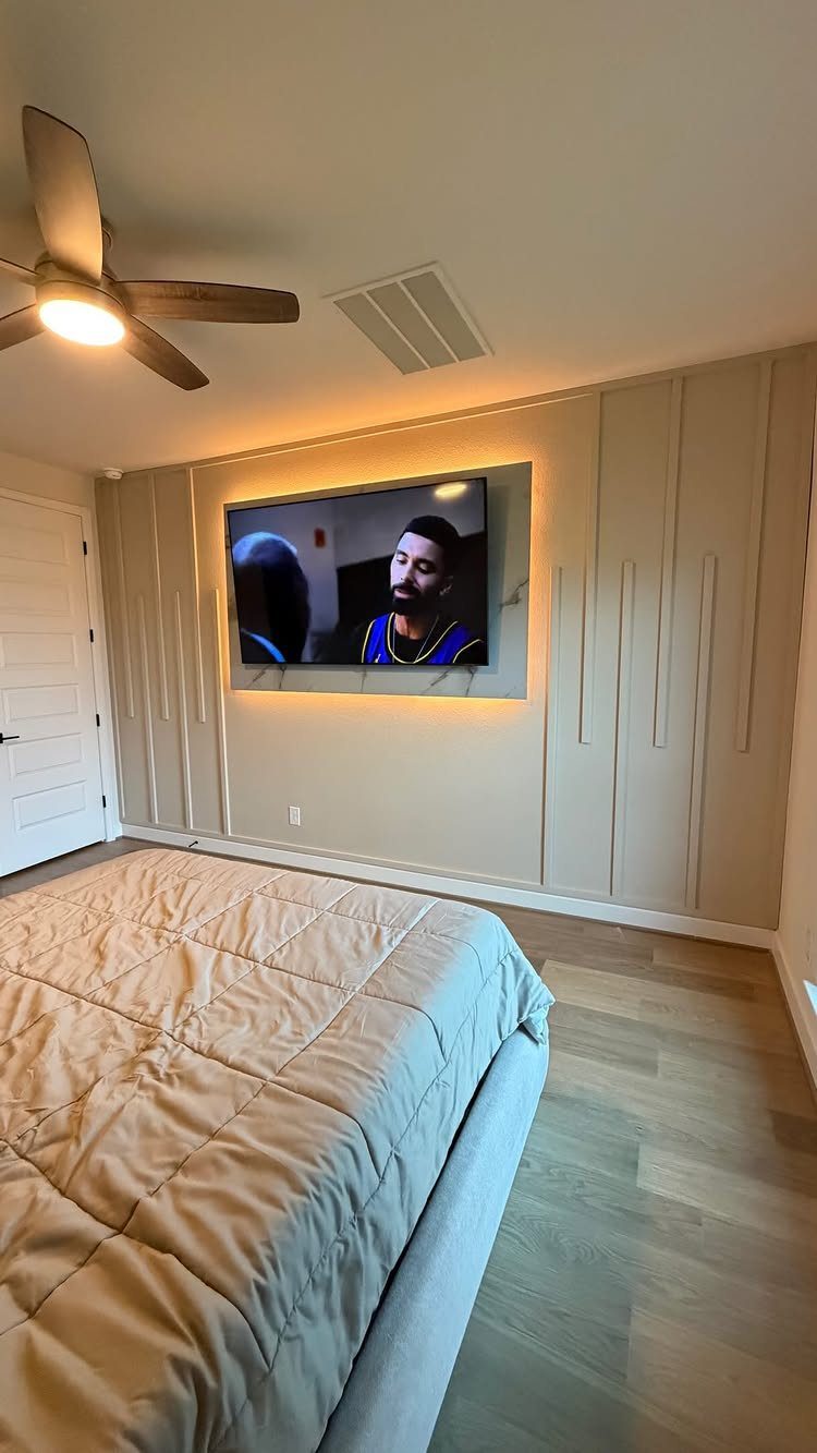 Beige vertical slat accent wall in a bedroom with a mounted television and bed.