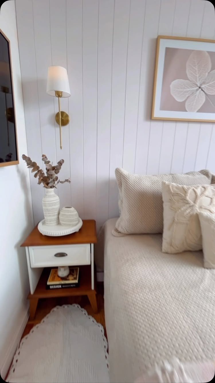 White vertical shiplap wall in a bedroom with a bed and wooden nightstand.