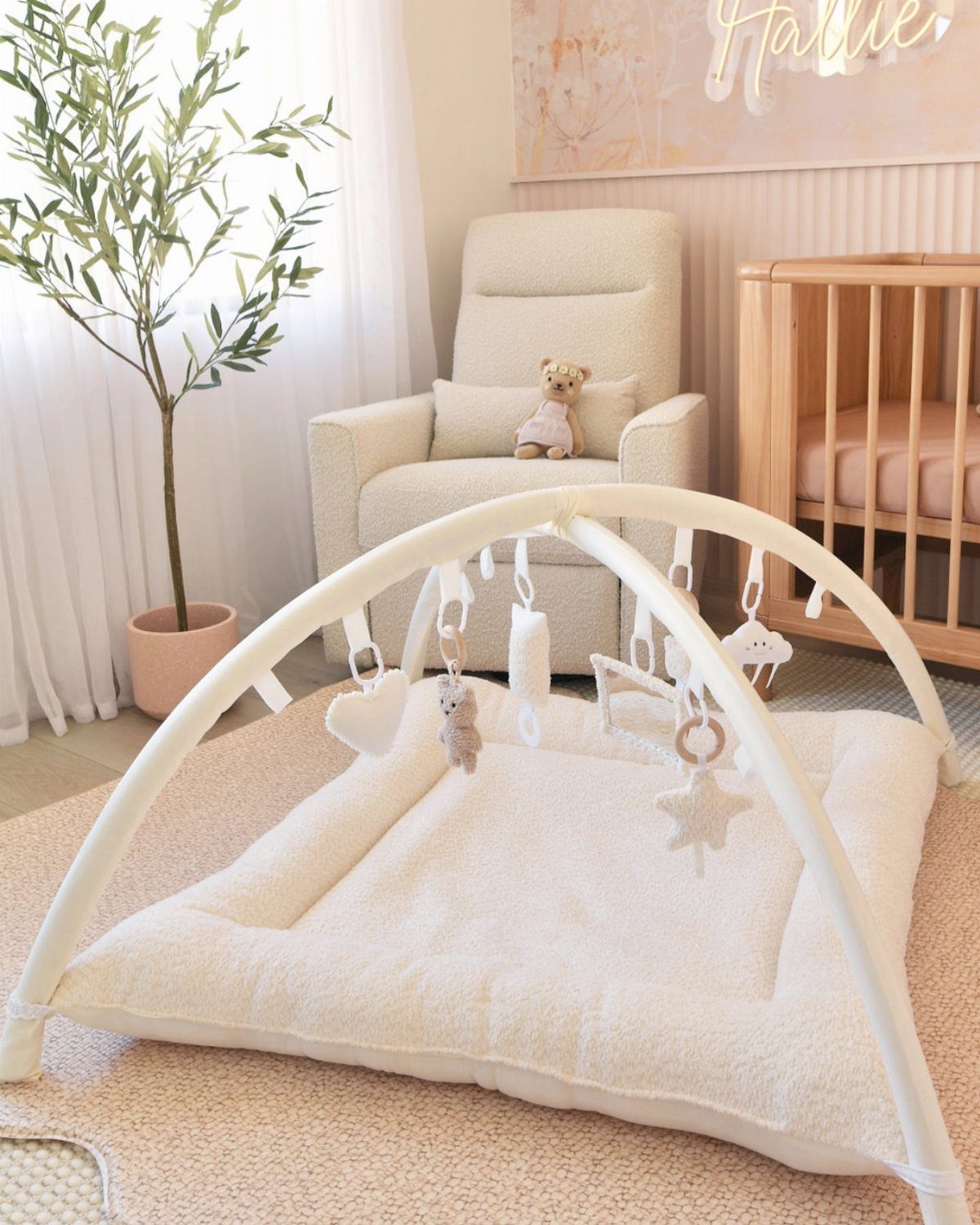 White baby activity gym on a beige rug in a neutral toned nursery.