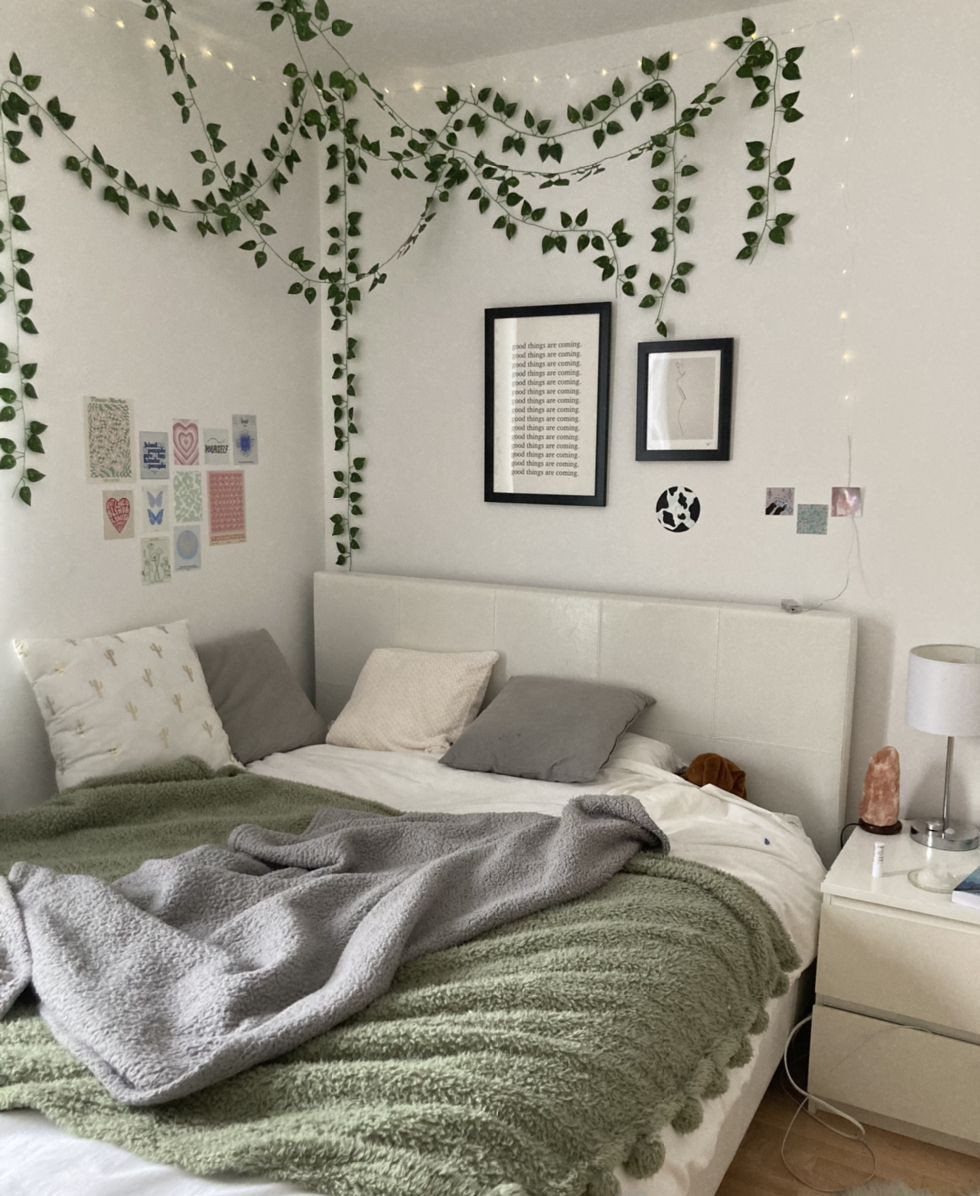 Bedroom with sage green bedding, white walls, and hanging ivy vines with fairy lights.