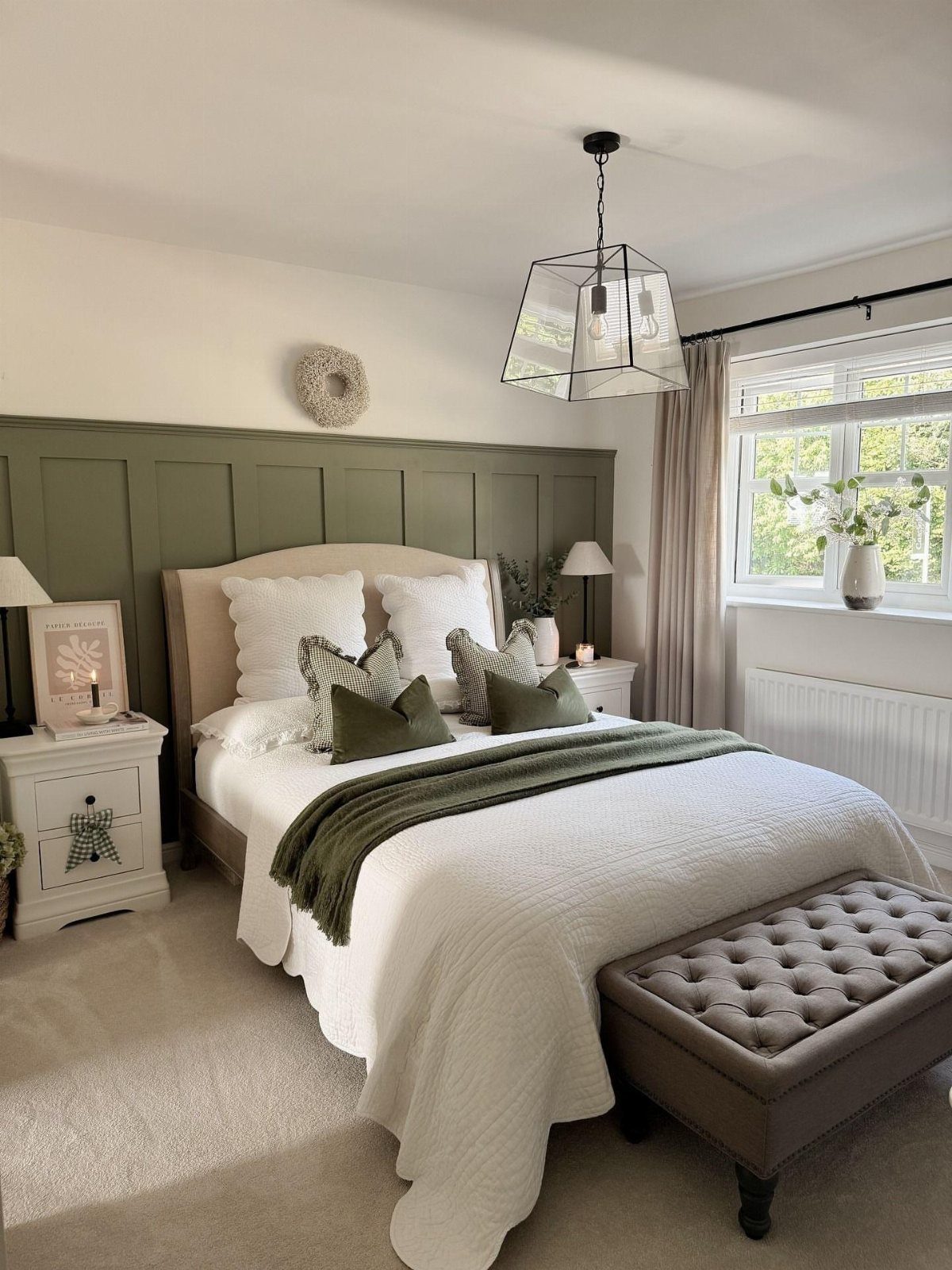 Bedroom with olive green wall paneling, white bedding, and a green throw blanket.