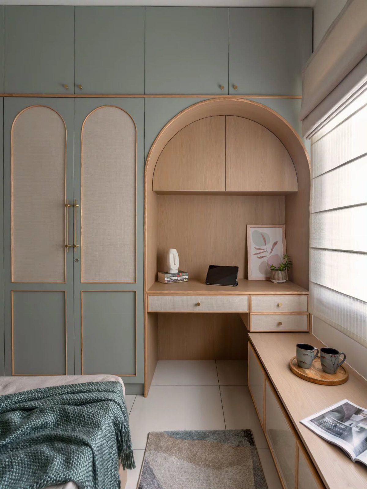 Sage green wardrobes and a light wood desk nook in a modern bedroom.