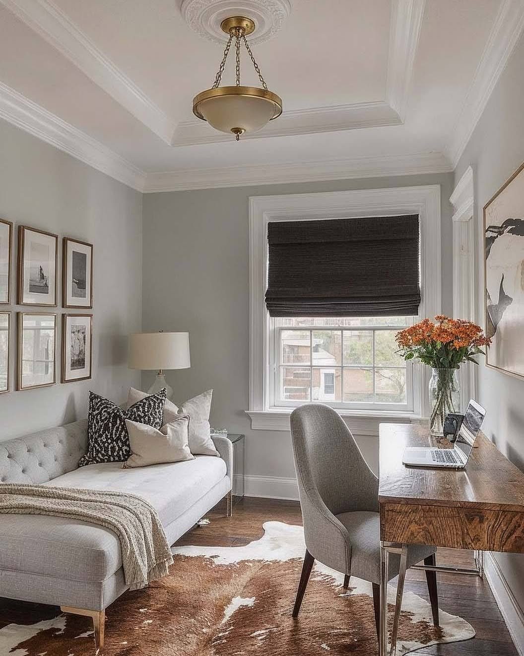 Grey daybed and wooden desk in a bright guest bedroom office combo room.