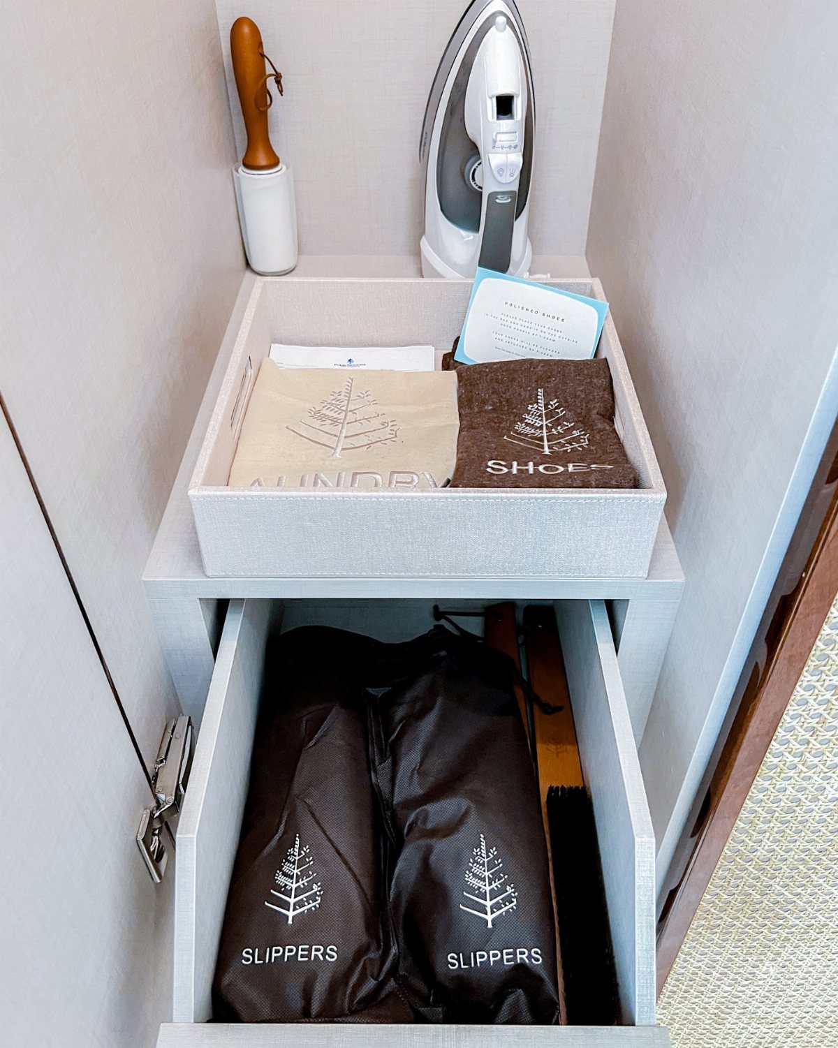 Guest amenities including an iron, lint roller, and slippers in a white closet.
