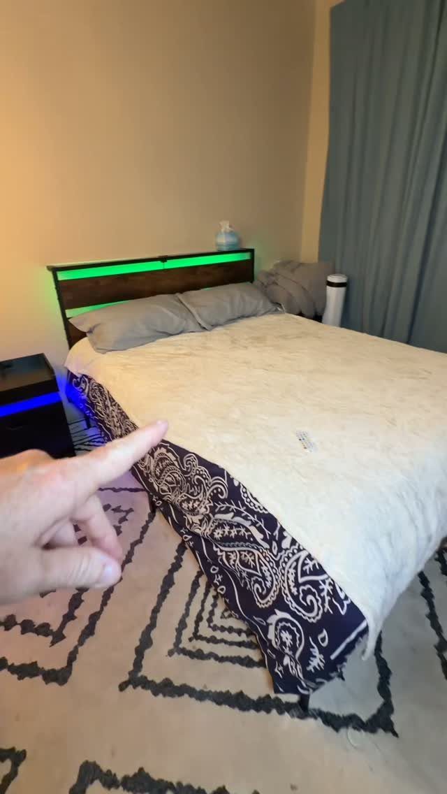 Bed with a dark wood headboard featuring integrated green LED lighting and bedding.