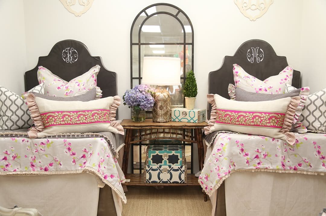 Two twin beds with dark brown monogrammed headboards and floral bedding in a bedroom.