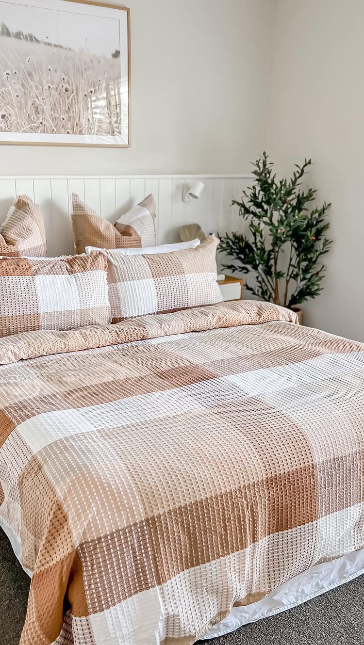 White wooden shiplap headboard behind a bed with brown checkered bedding.