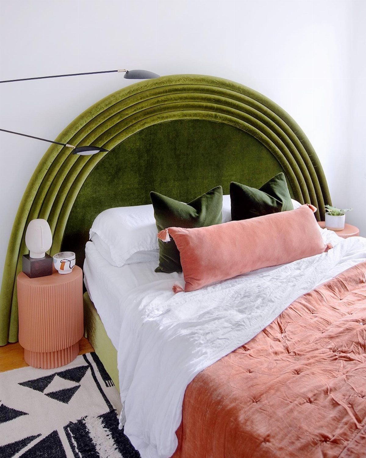 Arched olive green velvet upholstered headboard with concentric ridges in a modern bedroom