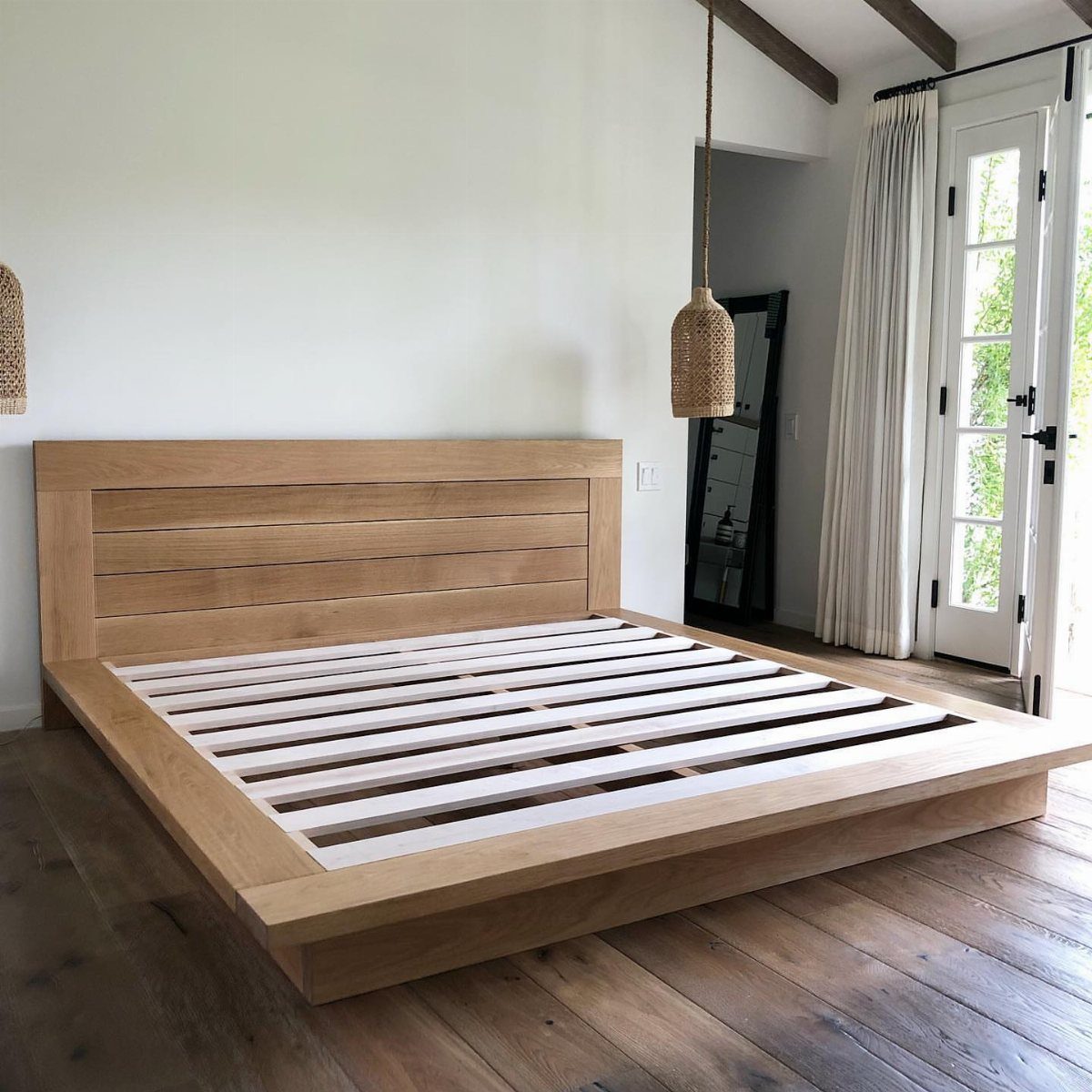 Wooden bed frame with a horizontal plank headboard in a bright bedroom