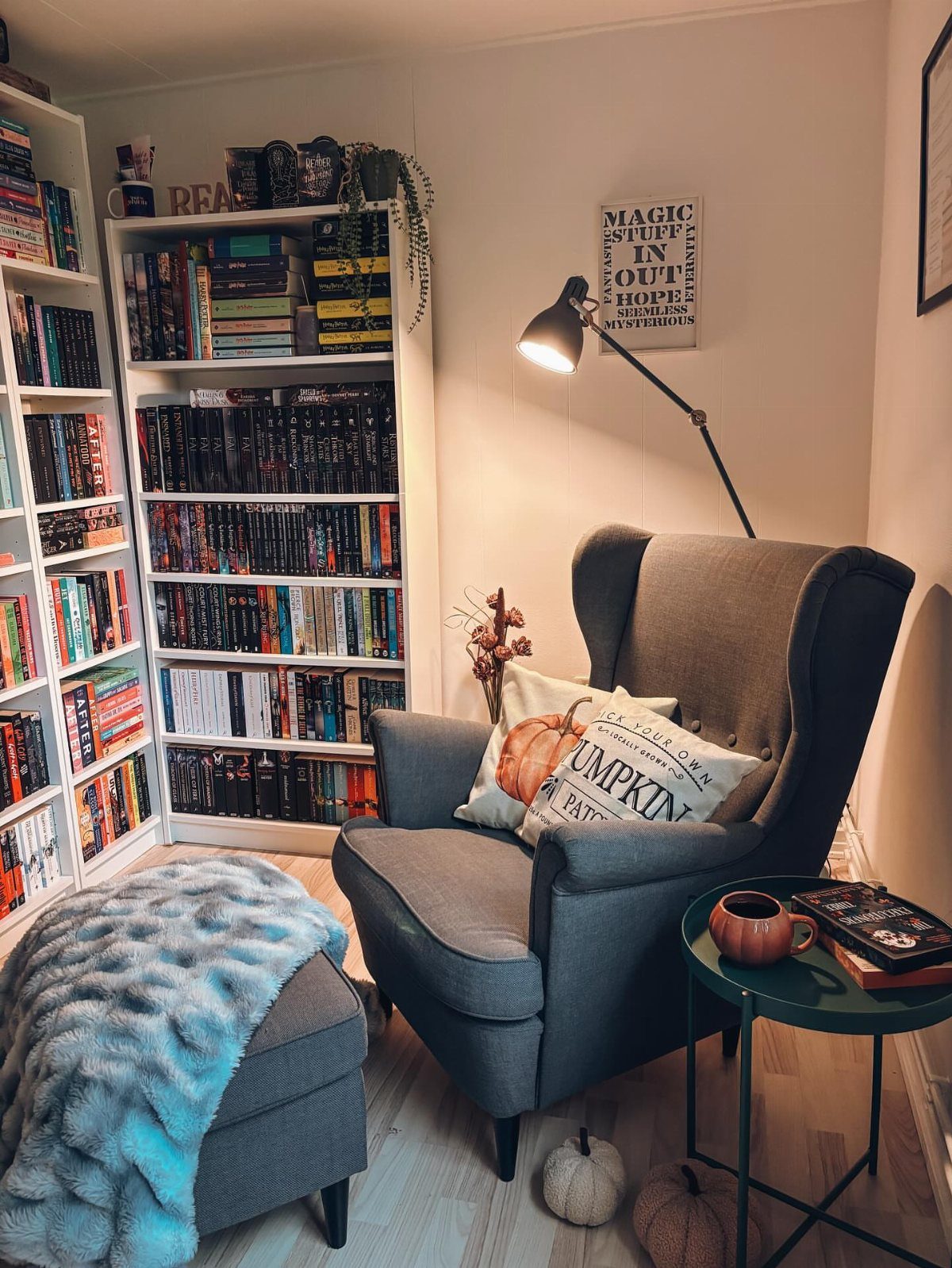 Grey wingback armchair and ottoman next to white bookshelves filled with many books.