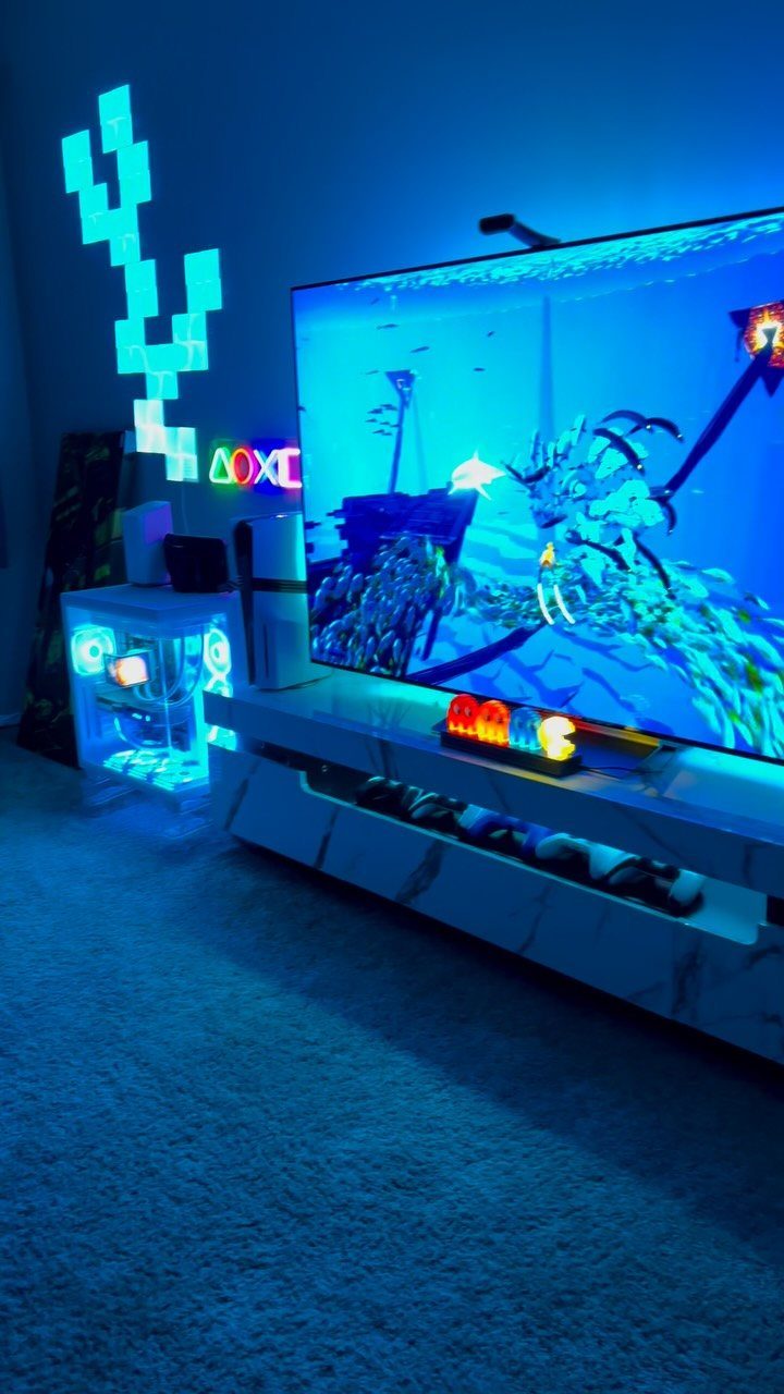 Gaming setup with a large screen, blue neon lighting, and marble media console.