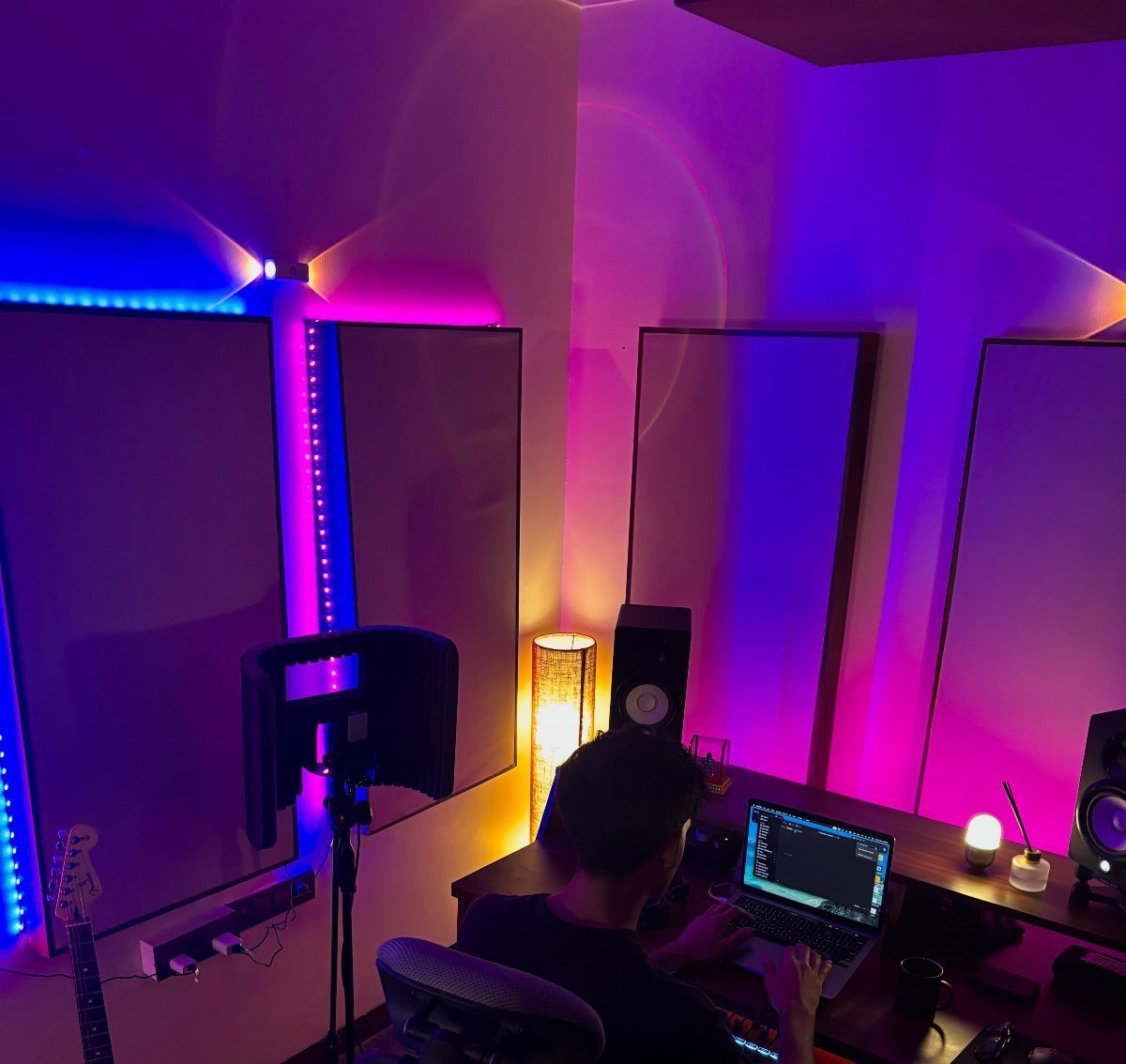 Person working at a laptop in a room with neon lighting and acoustic panels