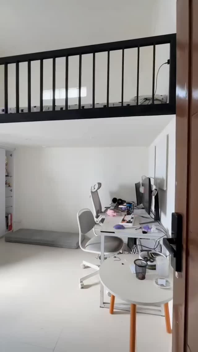 White desk and office chair set up under a black metal loft bed.