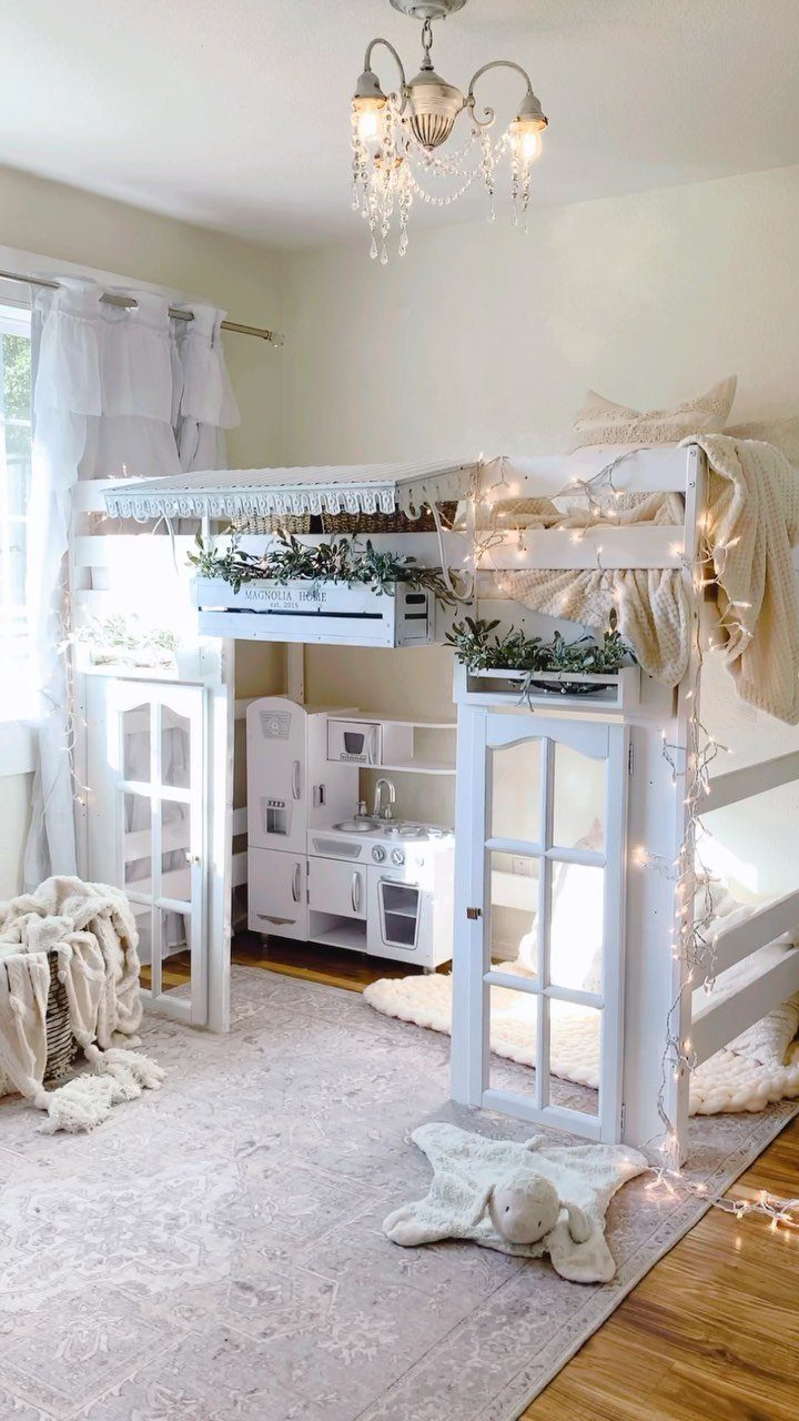 White wooden bunk bed with a play area and toy kitchen underneath.
