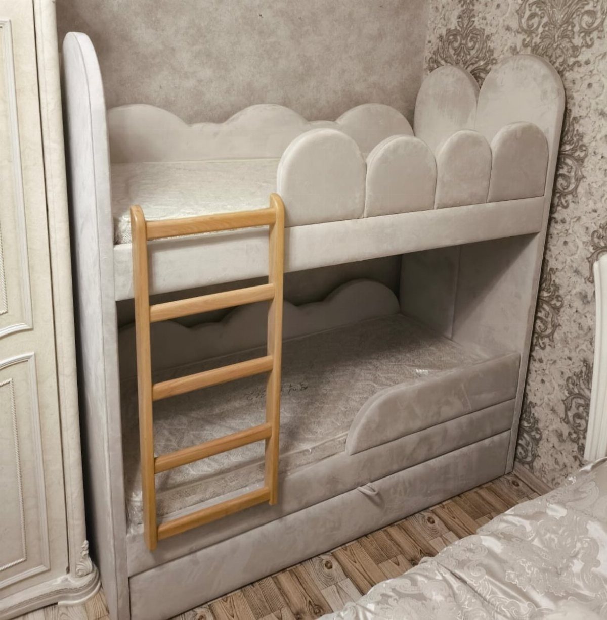 Light grey upholstered bunk bed with scalloped edges and a wooden ladder.
