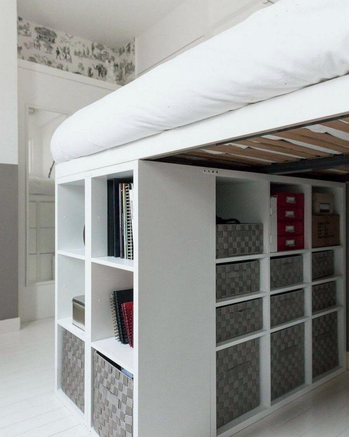 White loft bed with a white shelving unit and storage baskets underneath.
