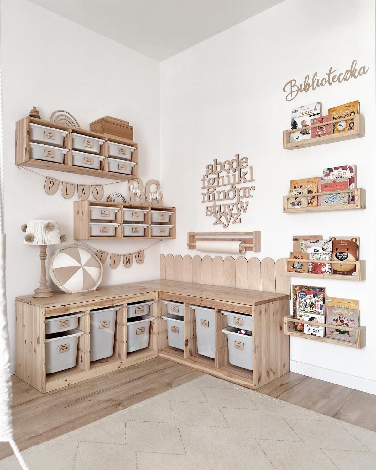 Light wood nursery storage and bookshelves with children's books against white walls.