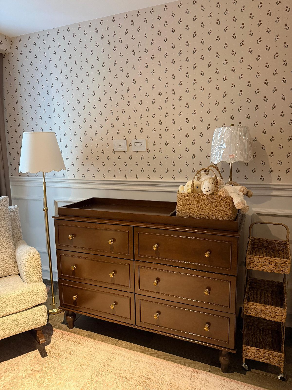 Brown wooden dresser with a changing tray and wicker basket in a nursery.