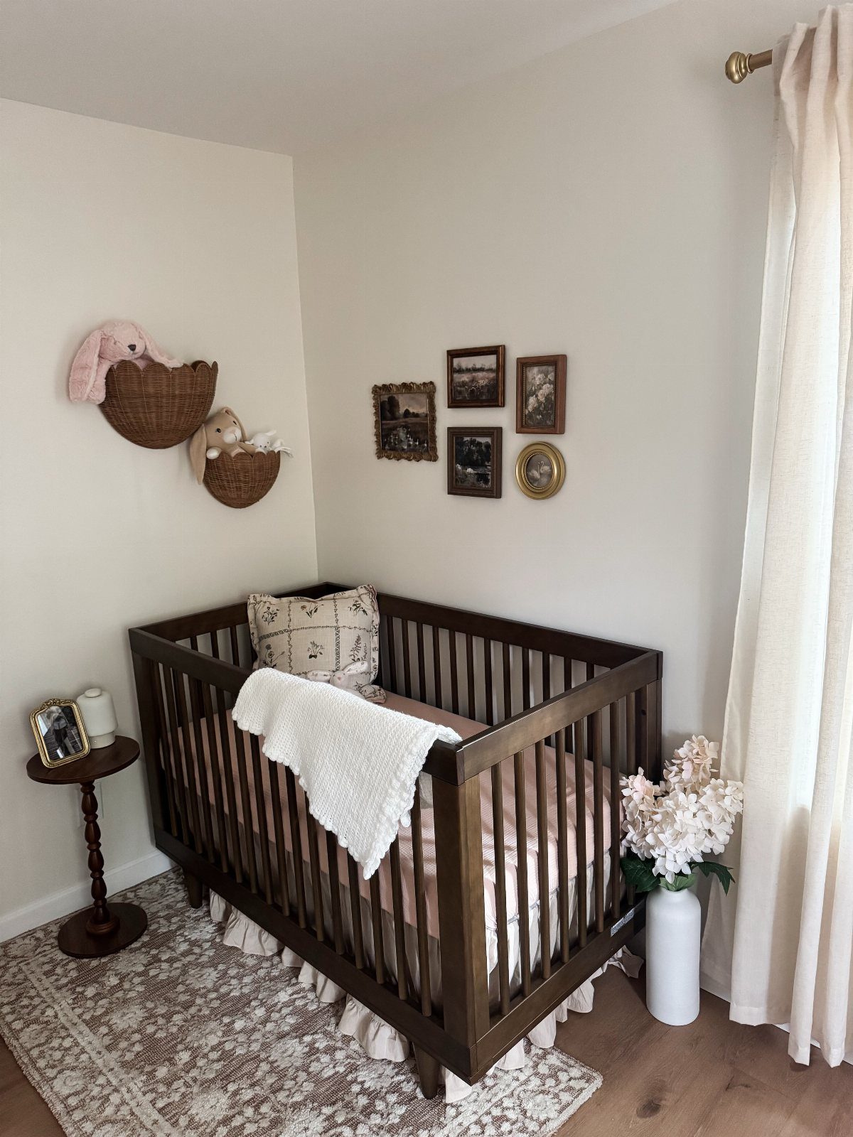 Dark brown wooden crib in a clean nursery with white walls and beige rug