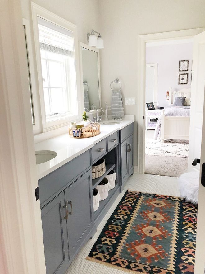 Bright bathroom with blue vanity, white countertop, and a window providing natural light.